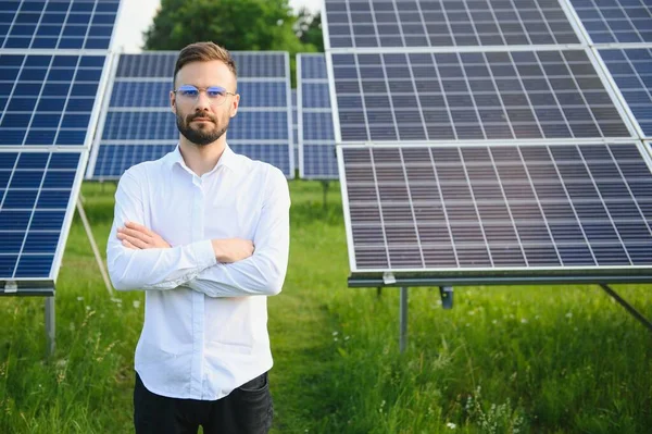 stock image Positive bearded male investor standing against photovoltaic panels producing alternative energy