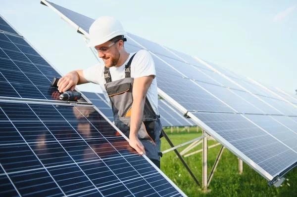 太陽電池モジュールを設置し 太陽電池アレイの構造をサポートする男性労働者の側面図 ソーラーパネルで作業中に安全ヘルメットをかぶっている電気技師 太陽エネルギーの概念 — ストック写真