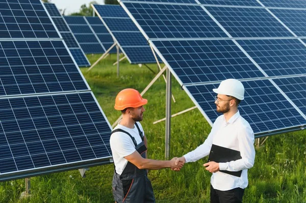 stock image Businessman and worker near solar energy batteries. Business client showing photovoltaic detail to foreman. Two men making deal