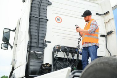 Elektrik kablolarını ticari bir kamyonun römorkuna bağlayan bir sürücü görüntüsü