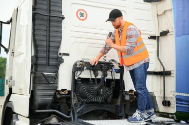 Elektrik kablolarını ticari bir kamyonun römorkuna bağlayan bir sürücü görüntüsü