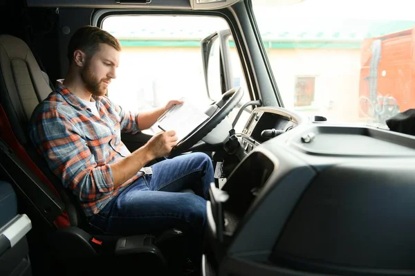 Side view of professional driver behind the wheel in truck\'s cabin