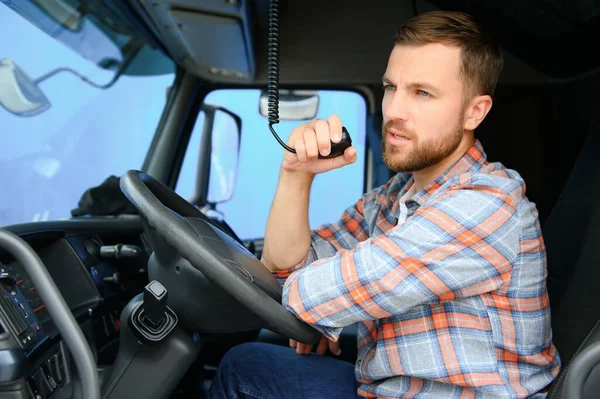 stock image Man trucker driving in a cabin of his truck and talking on radio transmitter