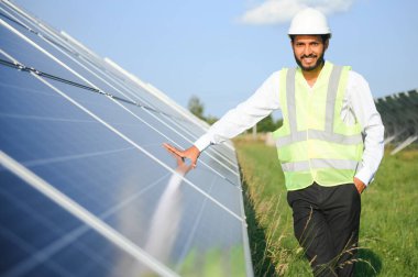 Erkek Arap mühendis güneş panelleri sıraları ile sahada duruyor
