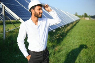 Erkek Arap mühendis güneş panelleri sıraları ile sahada duruyor