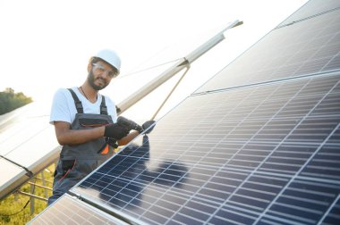 Üniformalı ve aletleri olan Hintli bir işçi güneş paneli çiftliğinde çalışıyor..