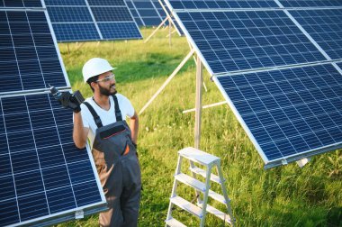 Hintli bir erkek işçi bir tarlaya güneş panelleri yerleştirmeye çalışıyor..