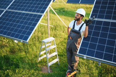 Güneş paneli yakınında çalışan üniformalı Hintli adam.