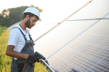 Güneş paneli yakınında çalışan üniformalı Hintli adam.