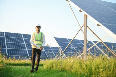 Genç, yakışıklı Afrikalı Amerikalı zanaatkârın yakın portresi koruyucu bir miğfer. Tulumlu, kameraya gülümseyen mutlu bir adam. Yavaş çekim