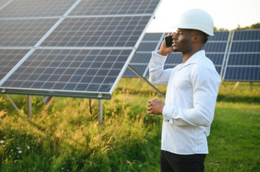 Afrikalı Amerikalı teknisyen güneş panellerinin bakımını kontrol ediyor. Güneş istasyonundaki siyah adam mühendisi.