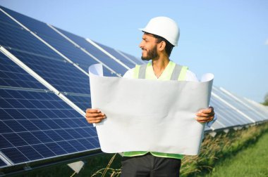 Erkek Arap mühendis güneş panelleri sıraları ile sahada duruyor