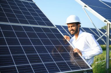 Erkek Arap mühendis güneş panelleri sıraları ile sahada duruyor