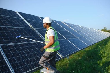 Düzenli Afrikalı işçi güneş panellerini özel süpürgeyle temizliyor..