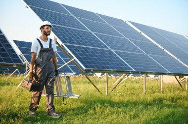 Hintli bir erkek işçi bir tarlaya güneş panelleri yerleştirmeye çalışıyor..