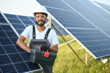 Hintli bir erkek işçi bir tarlaya güneş panelleri yerleştirmeye çalışıyor..