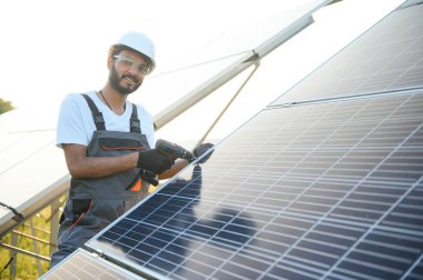 Hintli bir erkek işçi bir tarlaya güneş panelleri yerleştirmeye çalışıyor..