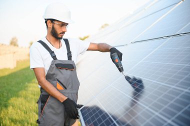 Erkek Arap mühendis güneş panelleri sıraları ile sahada duruyor