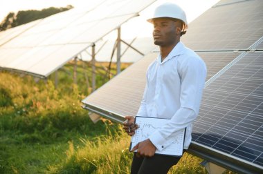 Genç, yakışıklı Afrikalı Amerikalı zanaatkârın yakın portresi koruyucu bir miğfer. Tulumlu, kameraya gülümseyen mutlu bir adam. Yavaş çekim