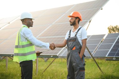 Güneş ekonomisi panelleri montajında çalışan işçiler işten sonra el sıkışıyorlar. Güneş panelleri kavramı.