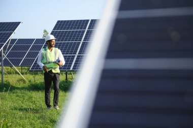 Erkek Arap mühendis güneş panelleri sıraları ile sahada duruyor