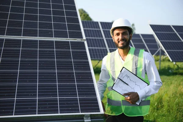 Erkek Arap mühendis güneş panelleri sıraları ile sahada duruyor
