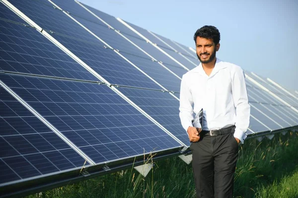 male engineer checks a photovoltaic (solar) plant and uses a recording tablet. Indian Man in uniform holding tablet