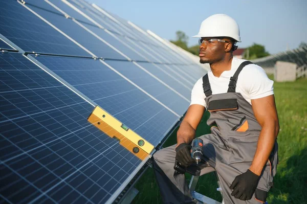 太陽電池パネルを維持するアフリカ系アメリカ人エンジニア 生態学的な太陽光発電所の構造の屋外で働く技術者 再生可能なクリーンエネルギー技術コンセプト — ストック写真