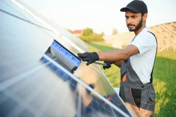 Indian man in uniform working near solar panel