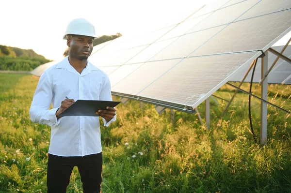 Genç, yakışıklı Afrikalı Amerikalı zanaatkârın yakın portresi koruyucu bir miğfer. Tulumlu, kameraya gülümseyen mutlu bir adam. Yavaş çekim