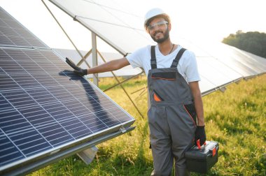 Güneş paneli yakınında çalışan üniformalı Hintli adam.