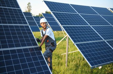 Hintli bir erkek işçi bir tarlaya güneş panelleri yerleştirmeye çalışıyor..