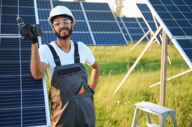 Erkek Arap mühendis güneş panelleri sıraları ile sahada duruyor