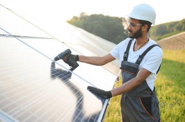 Erkek Arap mühendis güneş panelleri sıraları ile sahada duruyor