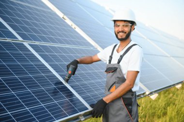 Güneş paneli yakınında çalışan üniformalı Hintli adam.