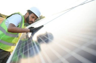 Erkek Arap mühendis güneş panelleri sıraları ile sahada duruyor