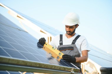 Hintli bir erkek işçi bir tarlaya güneş panelleri yerleştirmeye çalışıyor..