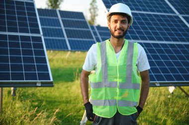 Erkek Arap mühendis güneş panelleri sıraları ile sahada duruyor