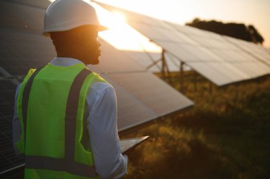 Genç, yakışıklı Afrikalı Amerikalı zanaatkârın yakın portresi koruyucu bir miğfer. Tulumlu, kameraya gülümseyen mutlu bir adam. Yavaş çekim