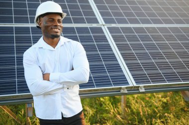 Afrikalı Amerikalı teknisyen güneş panellerinin bakımını kontrol ediyor. Güneş istasyonundaki siyah adam mühendisi.