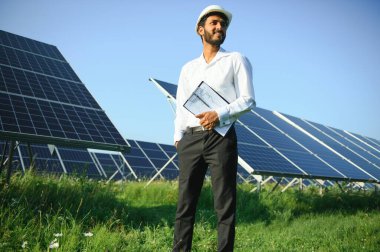 Erkek Arap mühendis güneş panelleri sıraları ile sahada duruyor