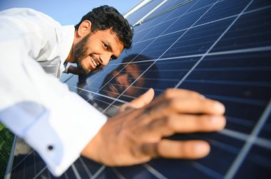 Erkek Arap mühendis güneş panelleri sıraları ile sahada duruyor