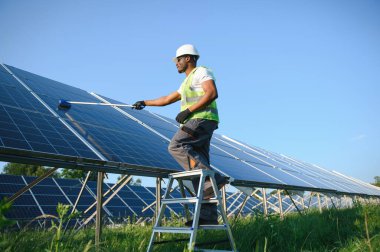 Düzenli Afrikalı işçi güneş panellerini özel süpürgeyle temizliyor..
