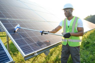 Düzenli Afrikalı işçi güneş panellerini özel süpürgeyle temizliyor..