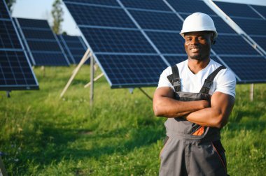 Güneş pili panellerini koruyan Afrikalı Amerikalı mühendis. Ekolojik güneş çiftliği inşaatında çalışan bir teknisyen. Yenilenebilir temiz enerji teknolojisi kavramı.