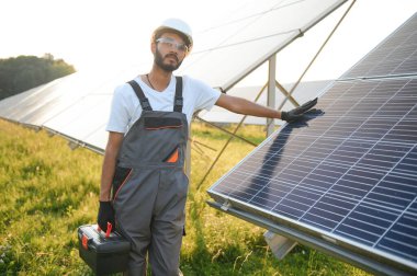 Hintli bir erkek işçi bir tarlaya güneş panelleri yerleştirmeye çalışıyor..