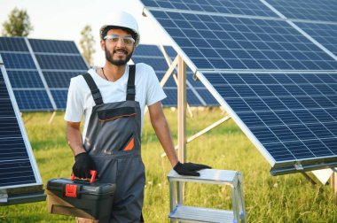 Güneş paneli yakınında çalışan üniformalı Hintli adam.