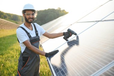Güneş paneli yakınında çalışan üniformalı Hintli adam.