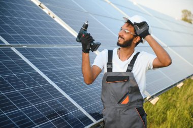 Güneş paneli yakınında çalışan üniformalı Hintli adam.