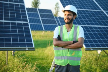 Erkek Arap mühendis güneş panelleri sıraları ile sahada duruyor
